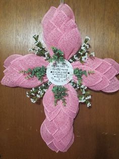 a cross made out of pink burlock with flowers on it and a plaque