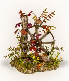 a wooden wheel surrounded by flowers and leaves on a white background with an owl sitting on the wheel