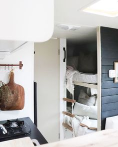 bunk beds are in the corner of this small room, with a sink and stove