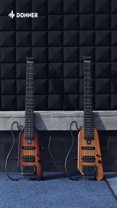 two guitars sitting side by side against a wall