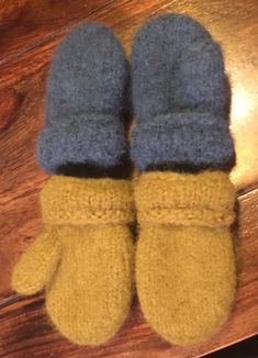 two blue and yellow mittens sitting on top of a wooden table