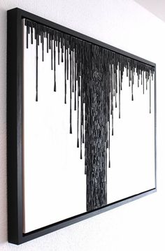 a black and white art piece hanging on the side of a wall with dripping paint