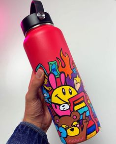 a hand holding a red water bottle with cartoon images on it