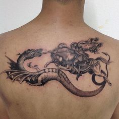 a man with a tattoo on his back has a dragon and rider on it's back