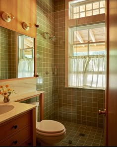 a bathroom with a toilet, sink and shower stall in it's corner next to a window