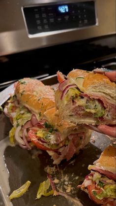 two sandwiches cut in half sitting on top of a metal tray next to an oven