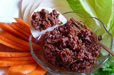 a bowl filled with meat and carrots next to lettuce on a plate