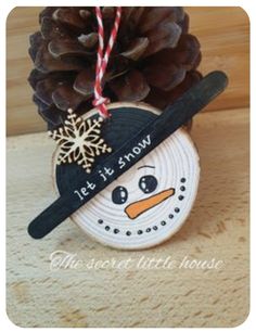 a pine cone with a snowman ornament hanging from it