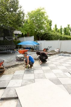 two men working on a patio in the backyard