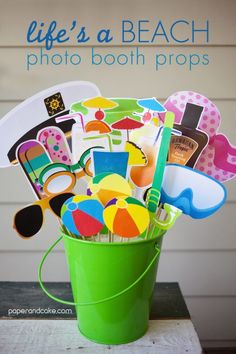 a green bucket filled with assorted beach items on top of a white wooden table