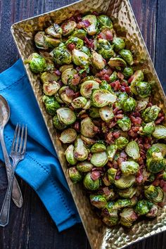 brussel sprouts in a wooden tray with silverware and blue napkin