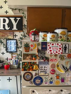 a refrigerator covered in lots of magnets next to a wall with pictures on it