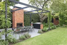 an outdoor dining area with brick fireplace and grill