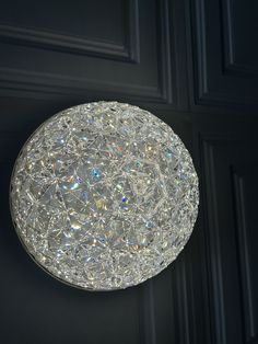 a round light fixture hanging from the side of a door with shiny glass beads on it