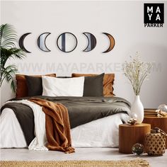 a bed room with a neatly made bed and three moon phases on the wall above it