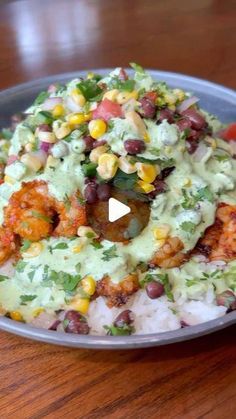 a bowl filled with rice, beans and vegetables on top of a wooden table next to a fork