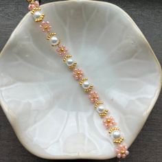 a white plate topped with a pink and gold beaded bracelet