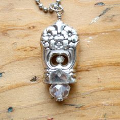 a silver necklace with a skull and crystal bead hanging from it's side