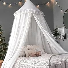 a white canopy bed sitting next to a christmas tree