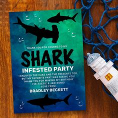 a shark themed birthday party card on a wooden table next to a bottle of water