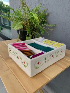 a white container filled with lots of different colored pencils on top of a wooden table