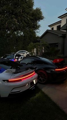 several cars are parked in front of a house at night with the lights turned on