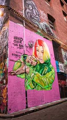 graffiti on the side of a brick building in an alleyway, with a woman's face painted on it