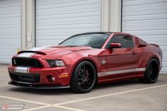 a red mustang parked in front of a garage door