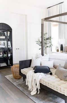 a living room filled with lots of white furniture and pillows on top of a rug