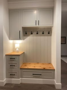 an empty room with white cabinets and wood counter tops on either side of the bench