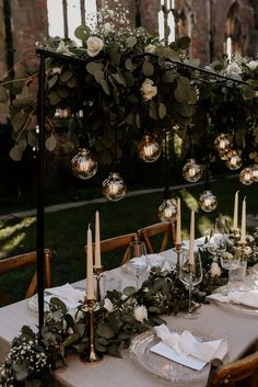 the table is set with candles, greenery and glass globes for an elegant touch