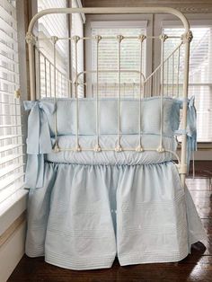 a white crib with blue bedding and pillows