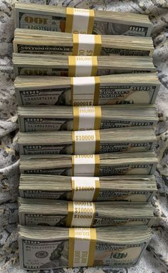 several stacks of money sitting on top of each other in front of a pile of blankets