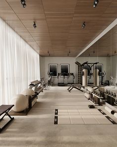 an empty gym with rows of exercise equipment and large windows in the back ground area