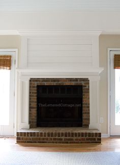 an empty living room with a brick fireplace