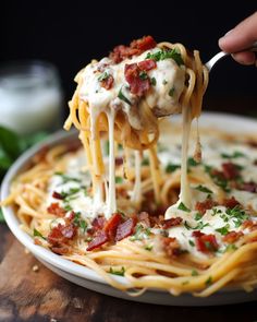 a person is holding a fork full of spaghetti with bacon and cheese on it,