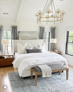 a large white bed sitting in a bedroom next to two windows