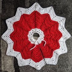 a red and white crocheted doily on the ground next to a pair of scissors