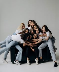 a group of young women sitting on top of each other in front of a white background