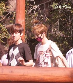 three young men standing next to each other on a wooden platform with trees in the background