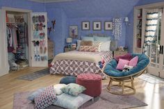 a bedroom decorated in blue and pink with lots of pillows on the bed, chairs, and other items