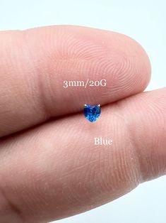 a person's finger with a tiny blue diamond on it