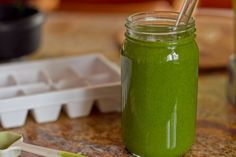 a green smoothie in a mason jar with a straw