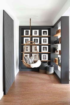 a living room filled with furniture and framed pictures on the wall behind a hanging chair