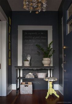 an entryway with a chalkboard on the wall and potted plants next to it