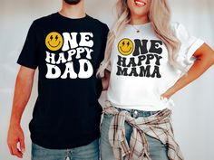 two people standing next to each other wearing t - shirts that say one happy dad and one happy mama