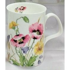 a white coffee cup with pink and yellow flowers painted on the side, sitting on a table