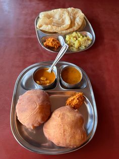 two silver trays filled with different types of food