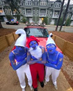 three people dressed as santa claus and snowmen standing in front of a car