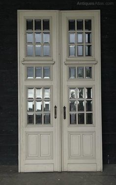 two white double doors with glass panes in front of a black wall